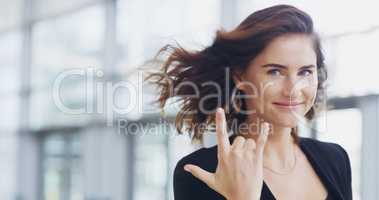 I make the business world rock. Cropped shot of a young businesswoman showing a shaka hand sign while walking through a modern office.