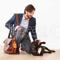 Have you been a good boy. A handsome businessman greeting his playful dog with a belly rub.