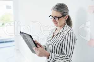 Utilising digital platforms to do business. Shot of a mature businesswoman using a digital tablet in an office.