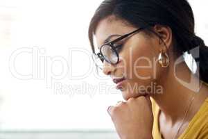 Thinking of what to do today. Cropped shot of an attractive young woman wearing spectacles and looking contemplative while sitting alone in her home.