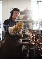 Grinding it down. Cropped shot of an attractive young female artisan using an angle grinder in her workshop.