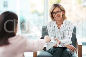 Compassionate listening is key. Shot of a mature psychologist offering her patient tissues during a therapeutic session.