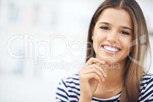 Her smile brightens up any room. Portrait of an attractive young woman relaxing at home.
