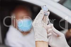 The cure to a deadly disease. Shot of an unrecognizable healthcare worker extracting liquid from a vial with a syringe at a drive through vaccination site.