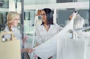 This one is my best-seller. Shot of a sales assistant helping a young woman in a clothing boutique.