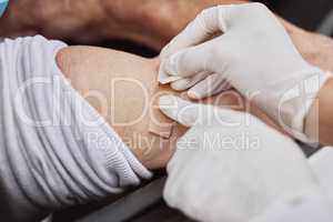 You are officially vaccinated. Shot of an unrecognizable healthcare worker applying a band-aid to a patient's arm at a drive through vaccination site.