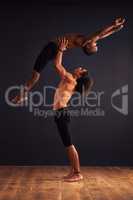 Together we can fly. Two male contemporary dancers performing a dramatic pose in front of a dark background.