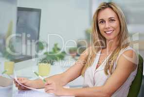 I love my job. Shot of an attractive female expressing positivity sitting at her desk at work.