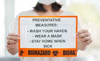 Heres how to protect yourself. Shot of a woman holding up a sign with a list of COVID-19 prevention measures.