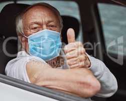 That wasn't so bad. Shot of a senior man showing a thumbs up in his car at a drive through vaccination site.