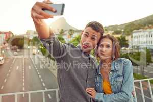 Lets get weird. Shot of a happy young couple taking a selfie together in the city.