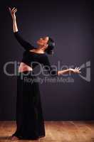 A feel for the theatrical. Female contemporary dancer in a dramatic pose against dark background.