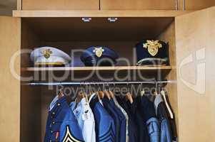 Not every hero wears a cape. Shot of various military jackets and hats hanging in a closet.