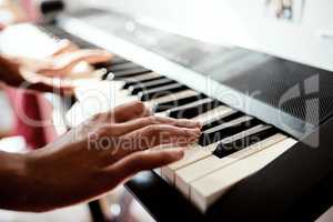 Piano keys unlock the language of the soul. Cropped shot of a woman playing music on a keyboard at home.