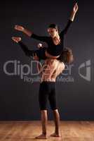 Strength and flight. A female and male contemporary dancer performing a dramatic pose in front of a dark background.