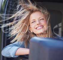 Feel the wind in your hair.... A young woman feeling the breeze in her hair through an open car window.