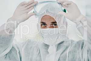 Time to annihilate this virus. Shot of a young man putting on his protective gear before the decontamination process.