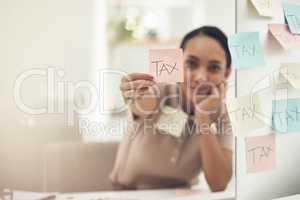 Be aware of different filing deadlines. Shot of a young businesswoman holding a note with "tax" written on it in an office.