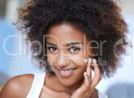 Keeping my face smooth. Portrait of an attractive young woman giving you a toothy smile while touching her skin.