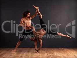 Trust and strength. Two male contemporary dancers performing a dramatic pose in front of a dark background.