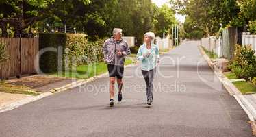 Try and keep up. Shot of a cheerful senior couple having a jog together outside in a suburb.