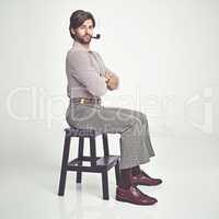 I rock. A young man with 70s style sitting in the studio and smoking a pipe.