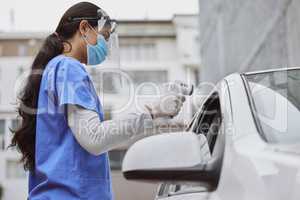 A quick temperature check. Shot of a young healthcare worker taking a patient's temperature at a drive through vaccination site.