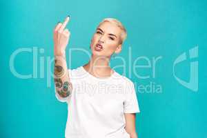 Stay in your lane. Studio shot of a young woman showing her middle finger against a turquoise background.