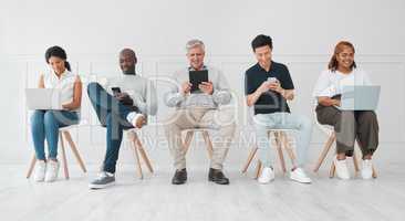 Making a few worthwhile connections while they wait. Shot of a diverse group of people using digital devices while sitting in line against a white background.