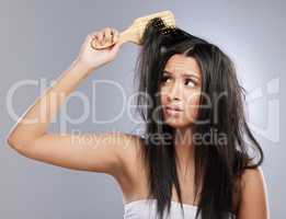 Follow good hair care practices to prevent damage. Studio shot of a young woman with damaged hair posing against a grey background.