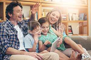 Connecting across borders with smart technology. Shot of a happy family making a video call on their digital tablet together at home.