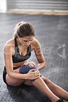 Protecting her knee from further injury. Shot of a young woman wearing a knee brace while working out in the gym.