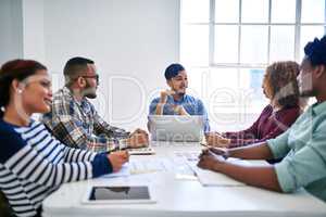 Were here to raise the bar. Cropped shot of a team of designers brainstorming together in an office.