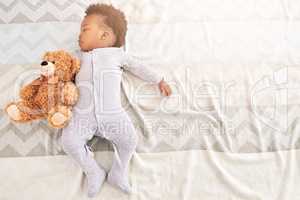 Little boy, big dreamer. High angle shot of a little baby boy sleeping on a bed with a teddy bear.