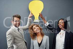 She always comes up with a bright idea. Studio portrait of three businesspeople standing against a gray background with a cutout lightbulb above their head.