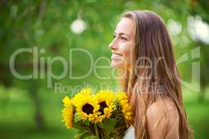Be like a sunflower, turn your face to the sun. Shot of a young woman holding a bunch of sunflowers outside.