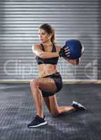 Working her core. Shot of a young woman working out with a medicine ball at the gym.