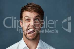 Time to get whacky. Studio portrait of a handsome young man sticking his tongue out against a dark background.
