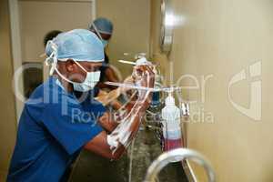 Hygiene is of the utmost importance. Shot of a team of surgeons sterilizing their arms and hands as part of a surgical routine.