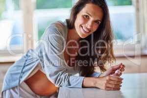 Snacking for two. Portrait shot of a pregnant woman eating yoghurt.