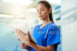 Time for a second opinion. Shot of a young nurse using a tablet while standing inside a clinic.