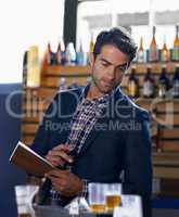 Calculating the consumption. Shot of a handsome young man doing stock take at a bar.