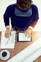 Getting work done more efficiently through the virtual world. High angle shot of a businessman wearing a VR headset while working in an office.