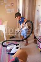 Tidy up time. Shot of a little boy vacuuming his bedroom at home.