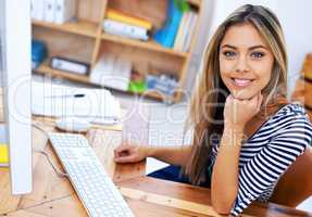 A keen and enthusiastic employee. A portrait of an attractive young professional sitting at her desk at work.