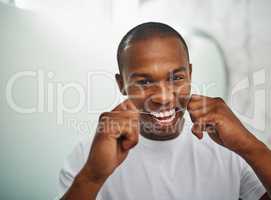 Reaching those areas my toothbrush cant. Portrait of a handsome young man flossing his teeth in the bathroom at home.