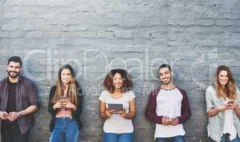 Access to information, when and where we want it. Portrait of a group of young people using their wireless devices together outdoors.