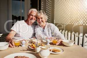 We still start our mornings together. Shot of a happy senior couple having a leisurely breakfast on the patio at home.
