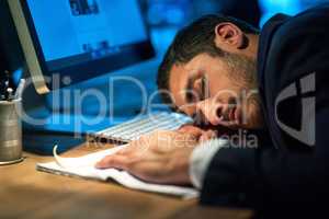 Working himself to death. Shot of an exhausted young businessman sleeping at his desk during a late night at work.