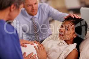 Giving birth can be tough, but so are you. Shot of a young woman giving birth with her husband supporting her in the background.